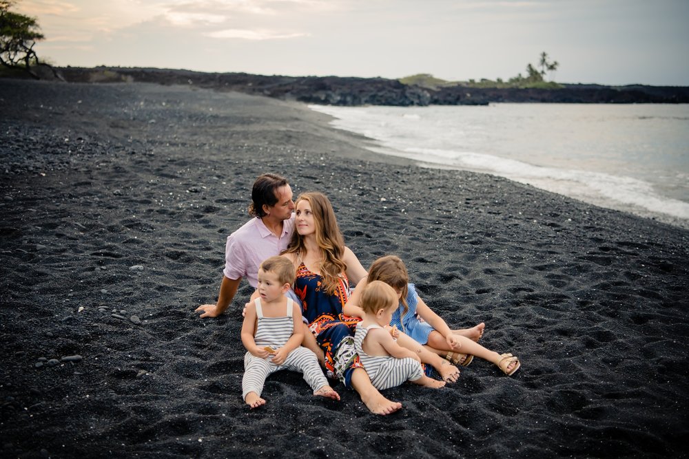 family sitting on black sand beach