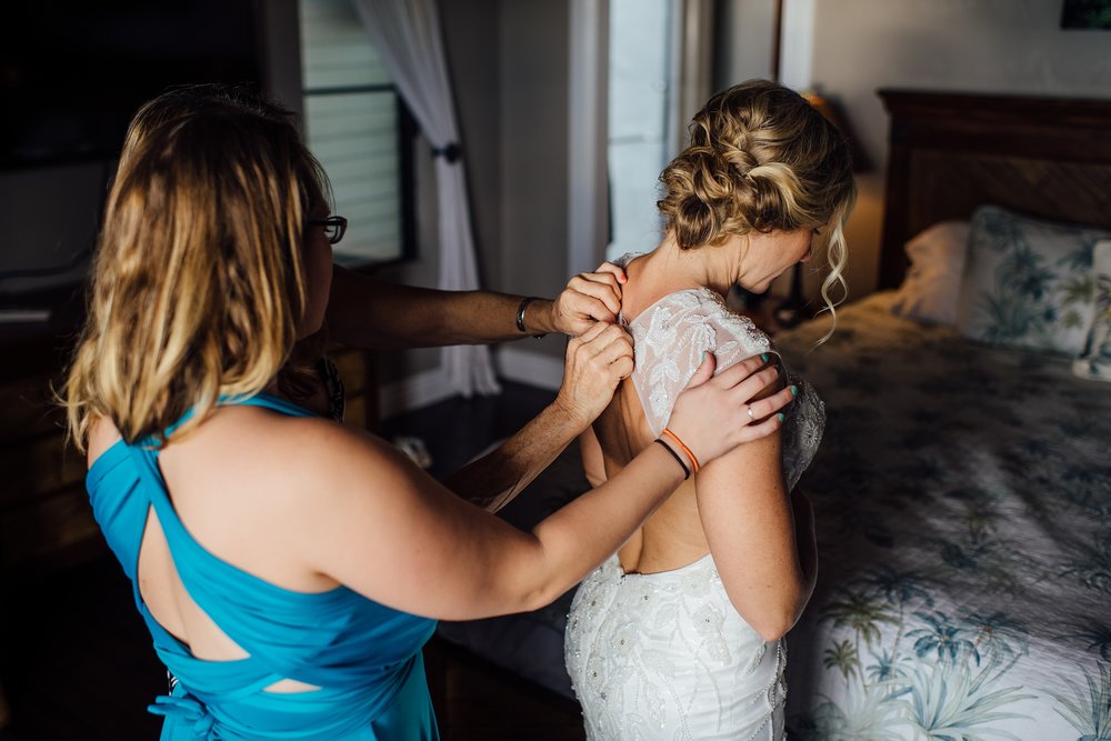 bride getting in her dress during Pine trees beach elopement
