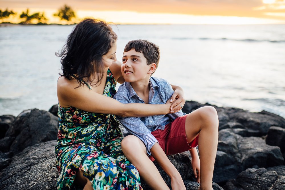 mom embraces son during sunset