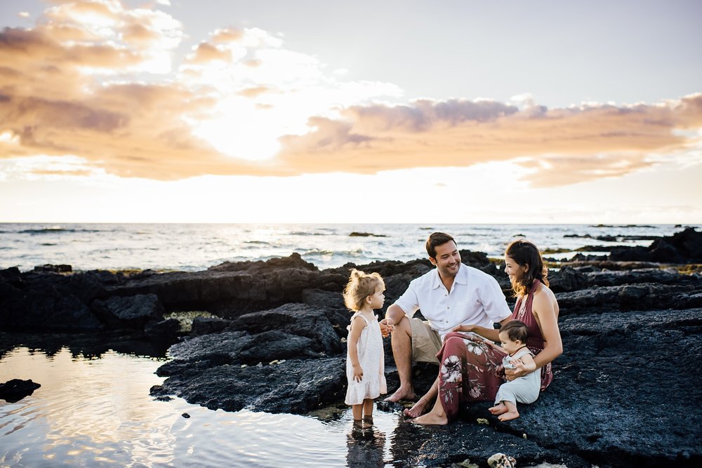 family sitting on the lava rocks during Hilton Waikoloa vacation