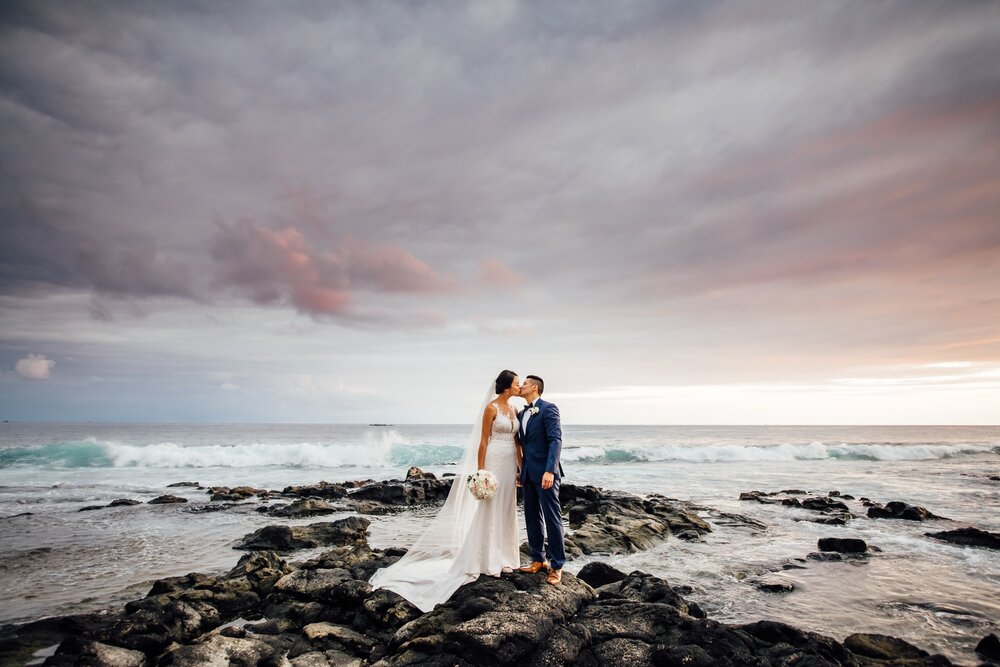 bride and groom kiss on the lava rocks
