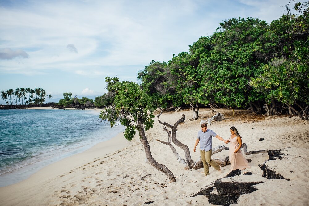 couple holding hands at Mahaiula Bay by engagement photographer