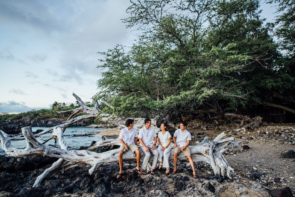 Family photography sitting on large drift wood in Puako Beach 