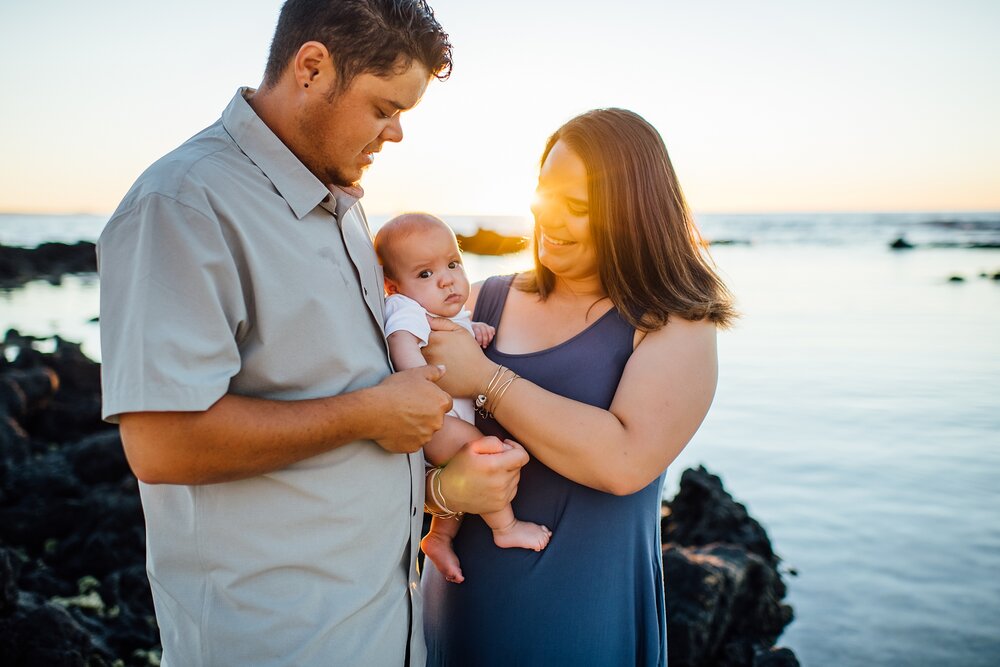 new growing family with their new little one on a beach in waikoloa at sunset