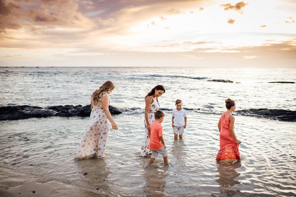 family dipping in the Hawaii waters during sunset