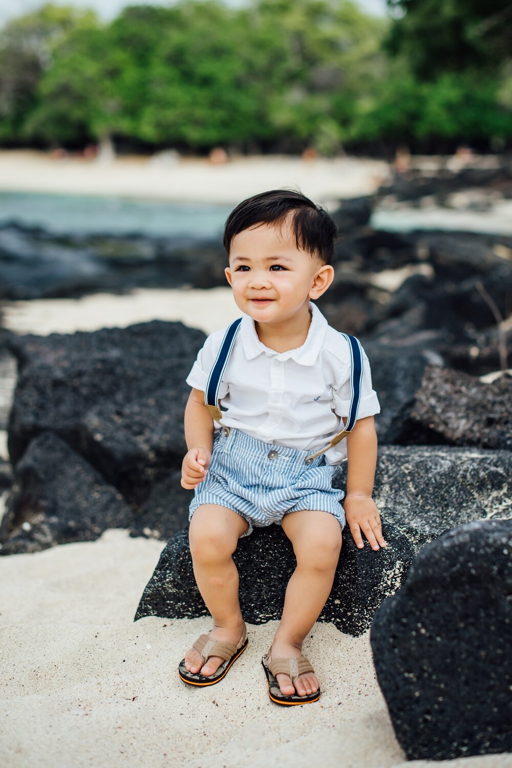 little boy sitting on the lava rock at Mahaiula Bay