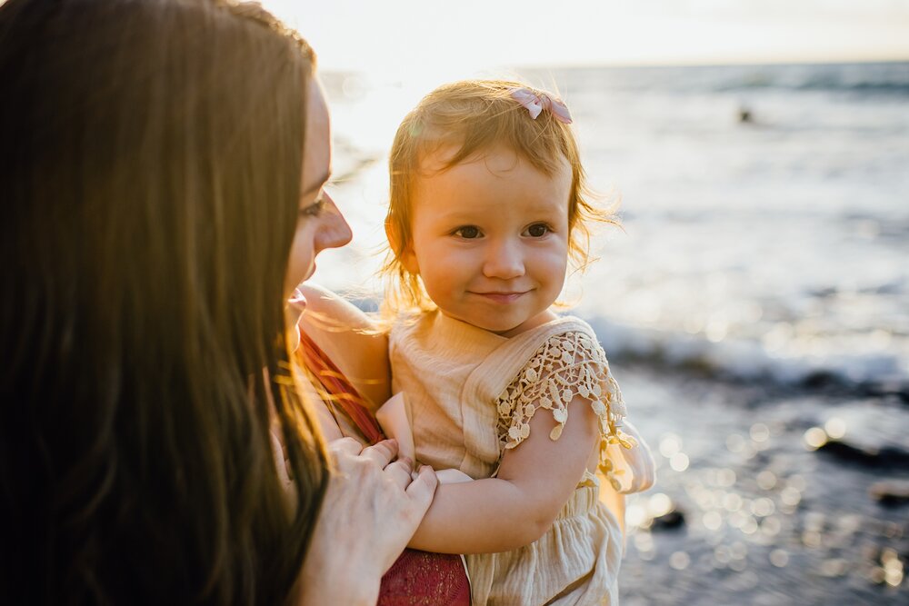 adorable baby with mom at the beach during sunset
