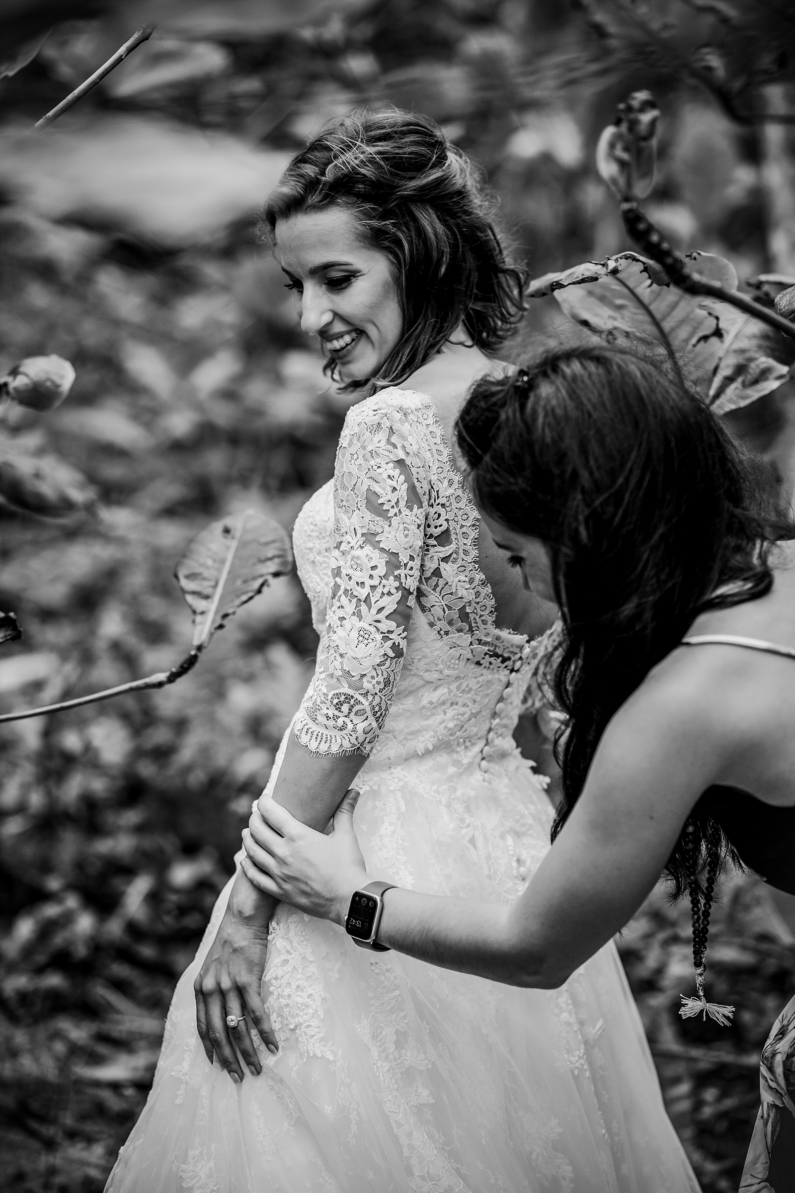 friend helping bride with dress