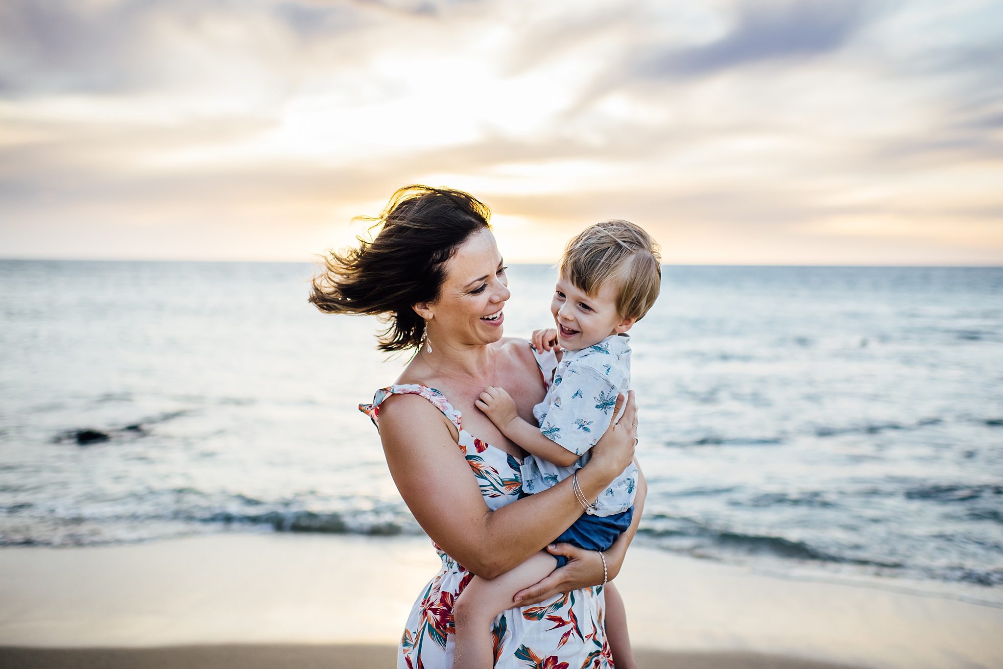 mom and little boy smiling and laughing during sunset