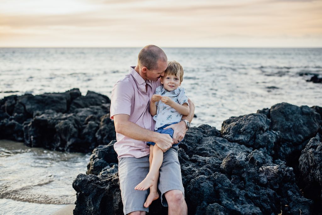dad hugging his son while sitting on lava rocks