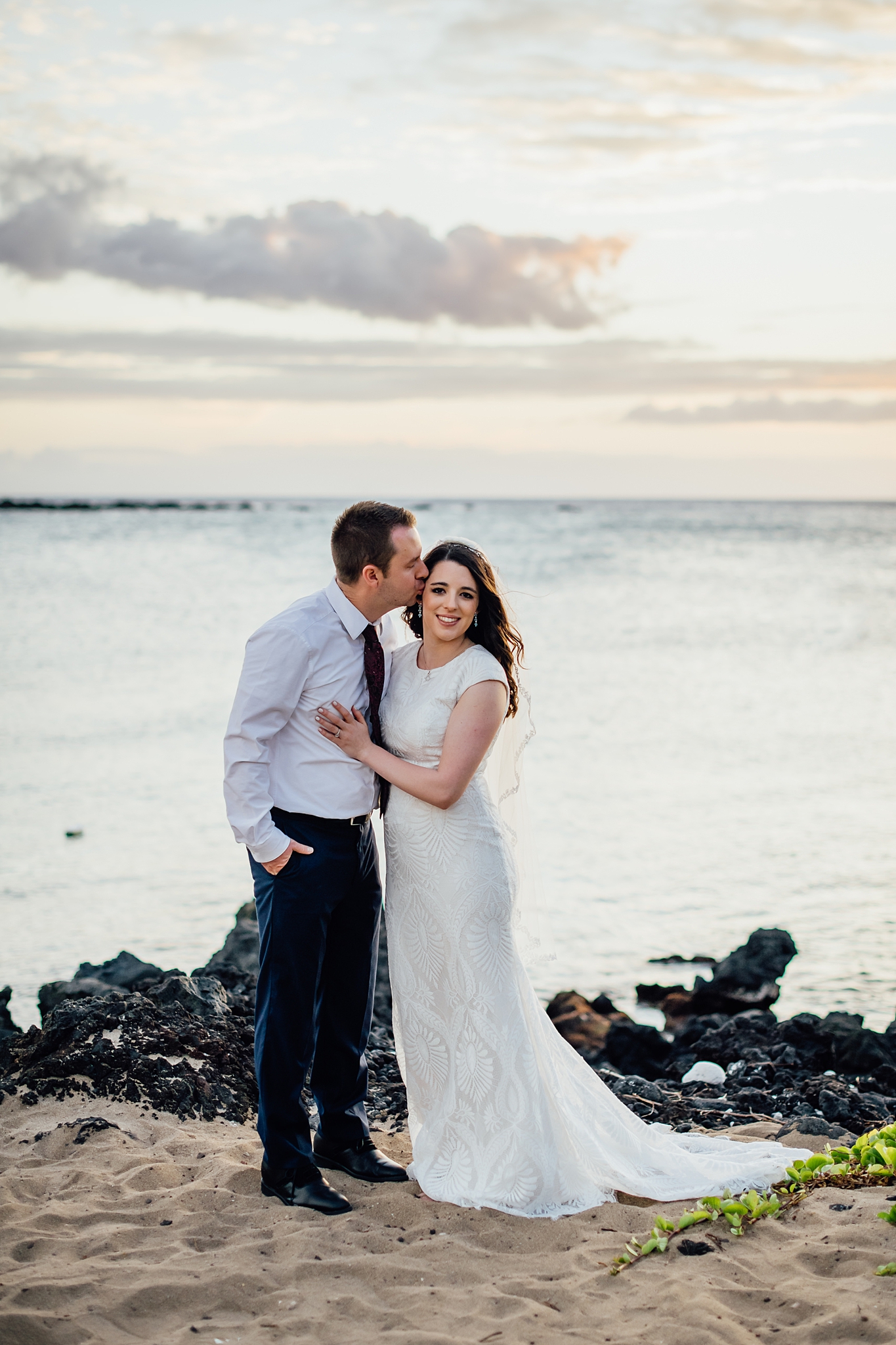 groom kissing bride's head at Kona beach