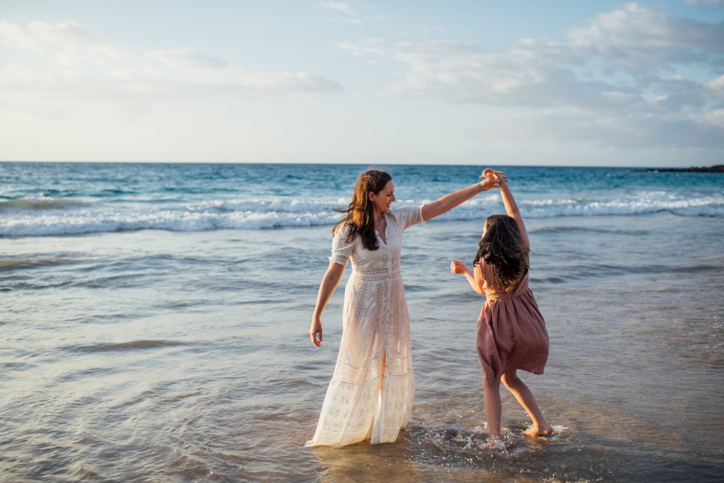 daughter twirls while holding mom's hand by holiday family photographer