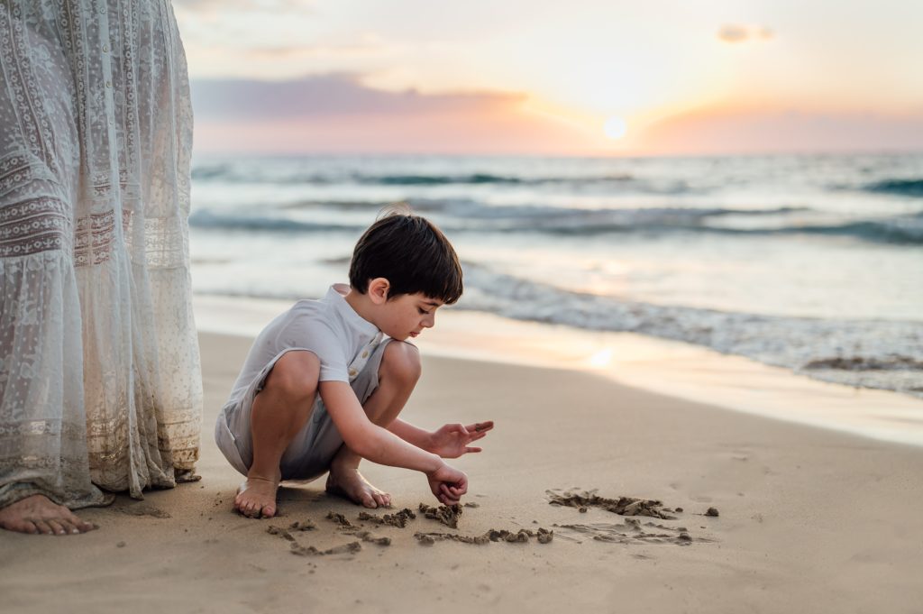 boy playing with sand on hawaii beach