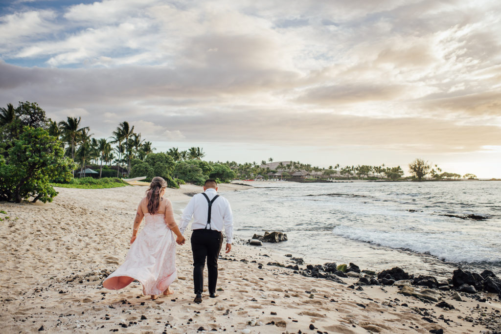 bride and groom walking along the shore holding hands