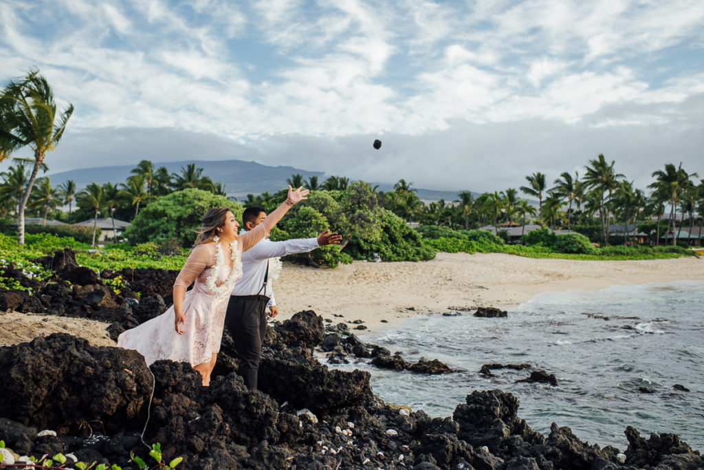 bride and groom throws lava stone to the sea