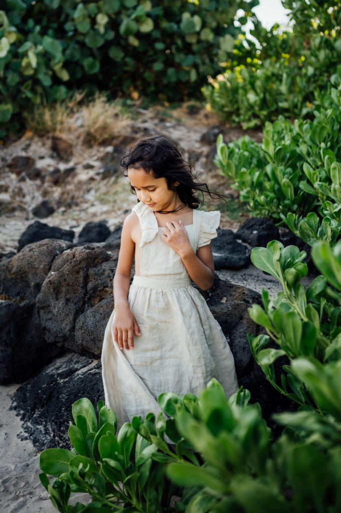 pretty young girl sitting on lava rocks by vacation photographer