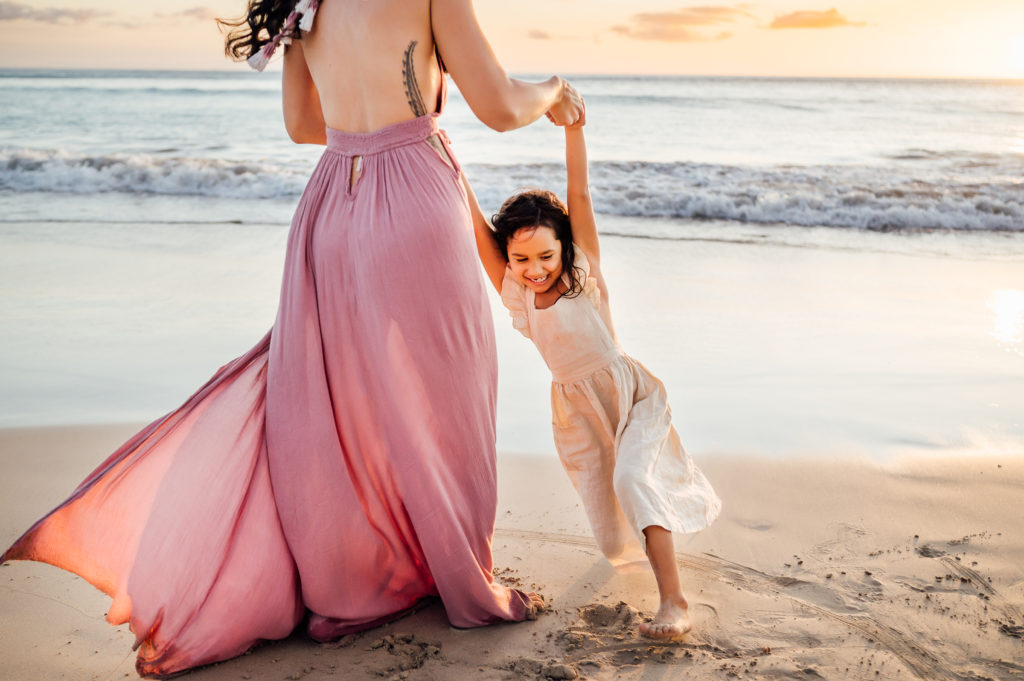 happy daughter playing with mom on the beach