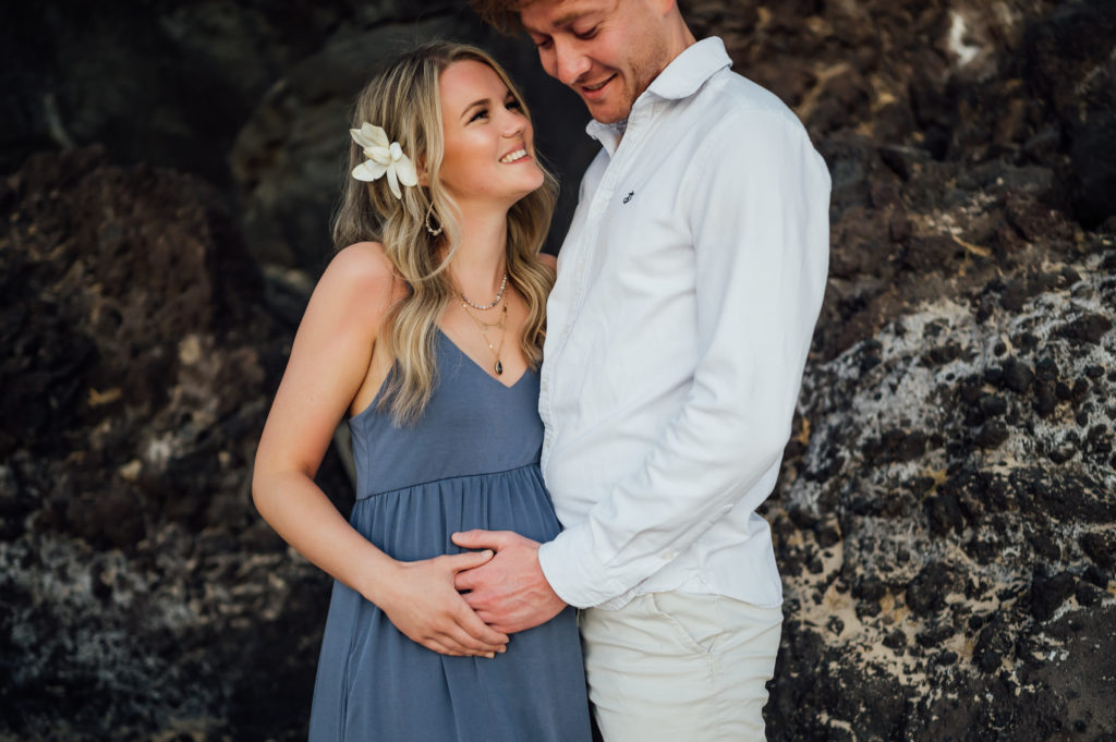 husband happily touches wife's baby bump during Westin Hapuna babymoon