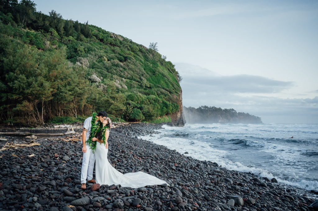 bride and groom kissing at a black sand beach