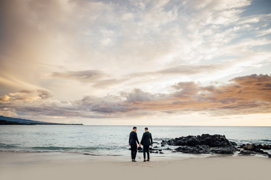 wedding couple holding hands on the beach during sunset