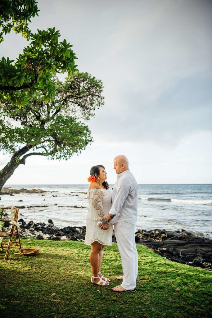 sweet photo of bride and groom holding hands at Hawaii beach by Ann Ferguson