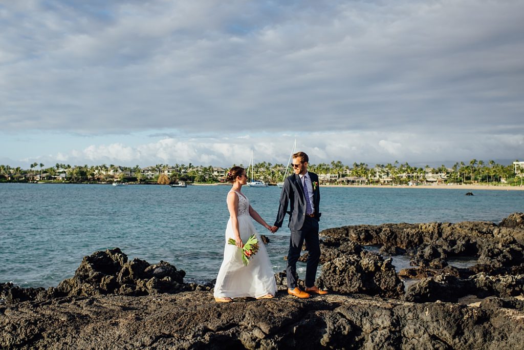 happy bride and groom standing on the lava rocks during sunset