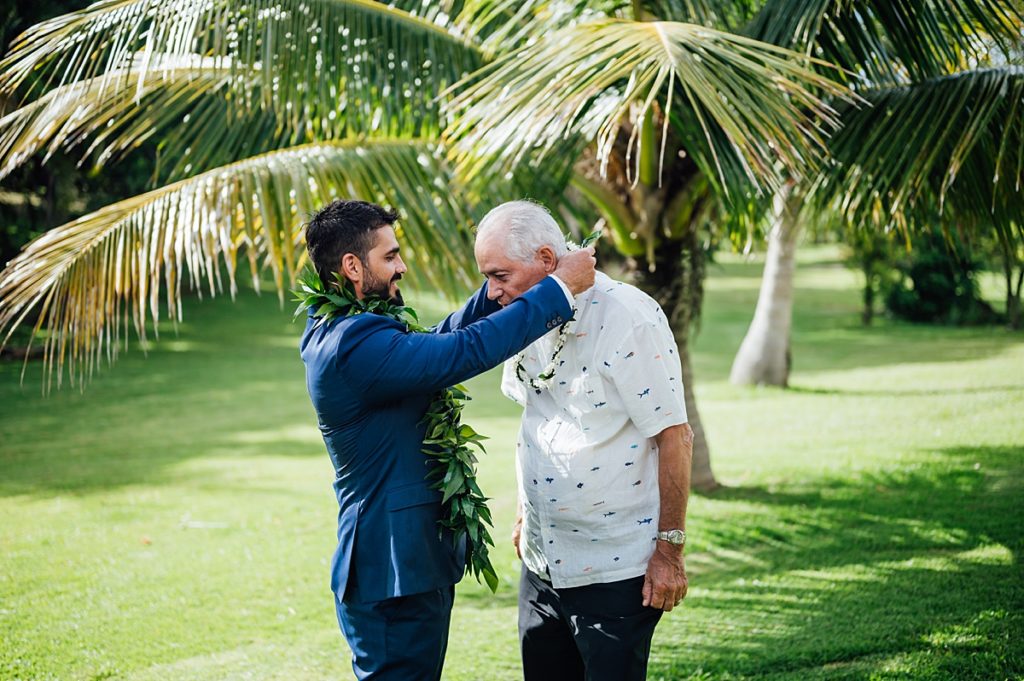 groom putting on a lei to his dad 