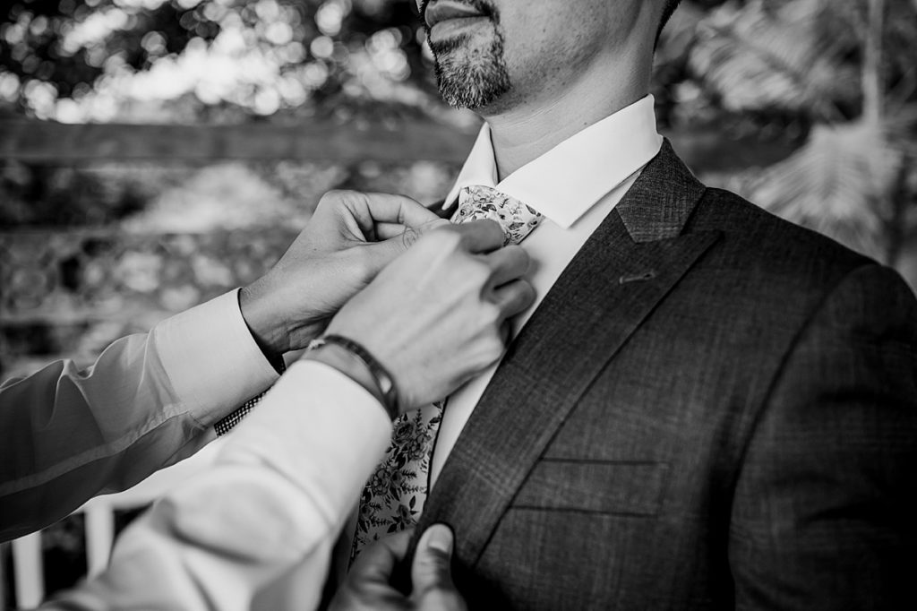 groom wearing his tie with groomsman's help