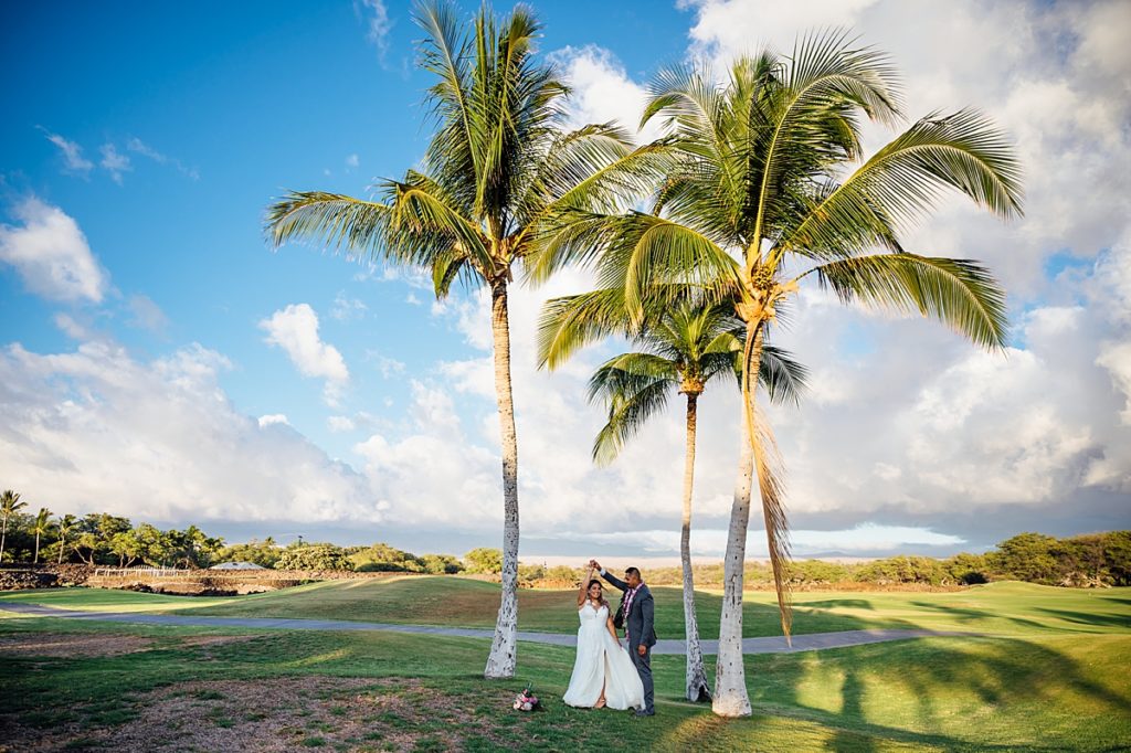 bride twirling under the coconut trees during their Hawaii wedding