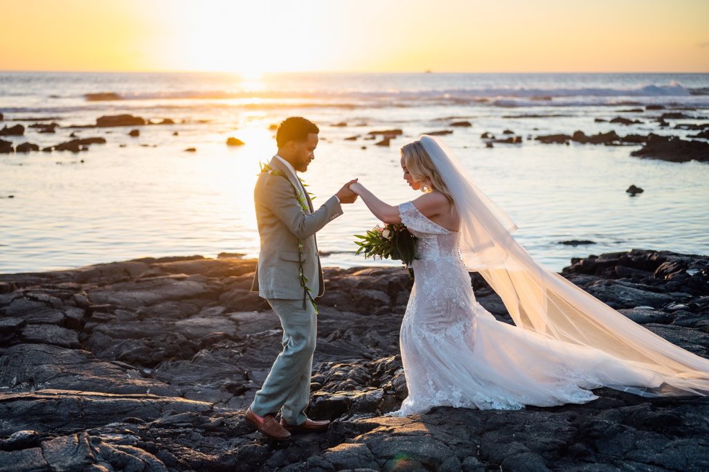 newlyweds holding hands on the lava rocks during sunset