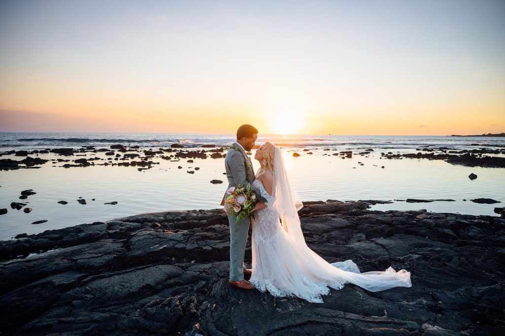 newlyweds facing each other on the lava rocks in Hawaii
