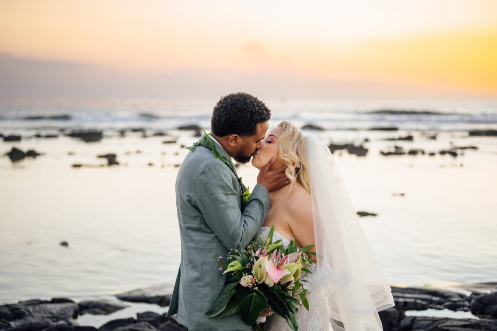 bride and groom kiss at the beach during golden sunset