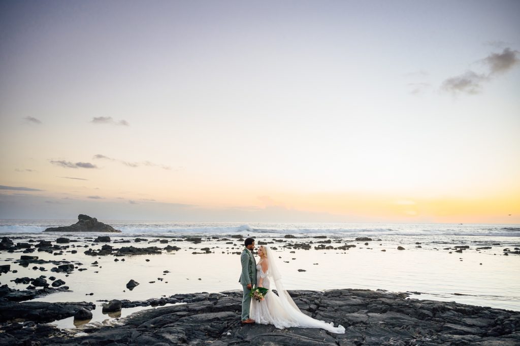 newlyweds on the lava rocks at the beach