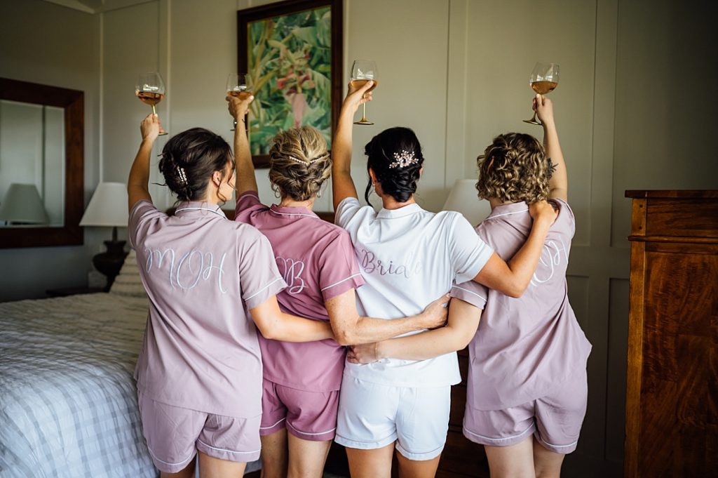 bride with her bridesmaids in pajamas raising their wine 