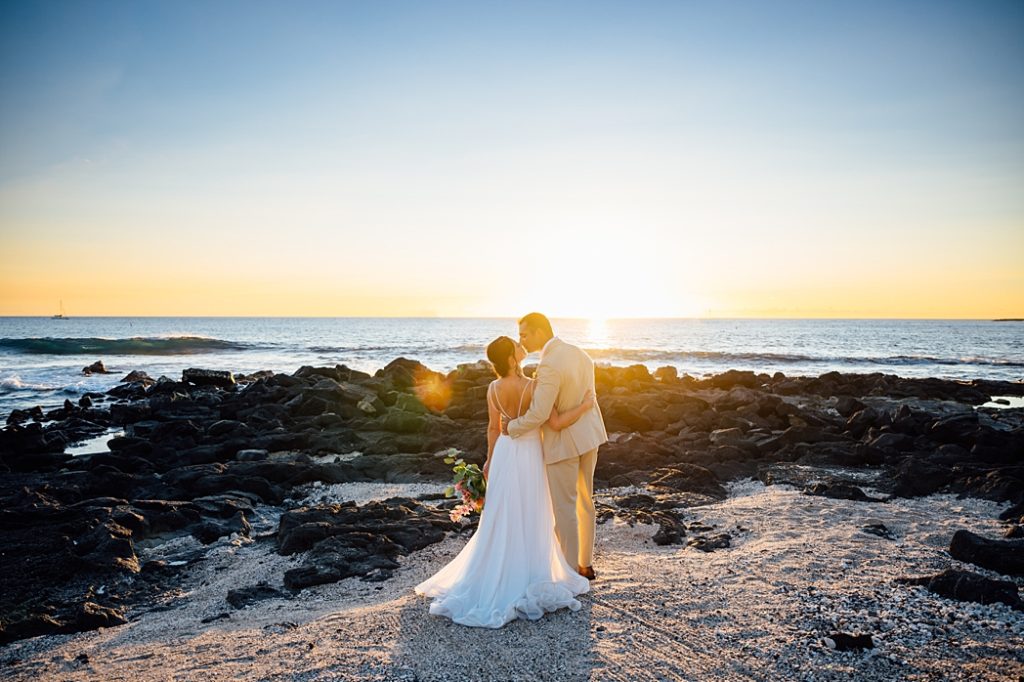 bride and groom kiss under the Big Island golden sunset