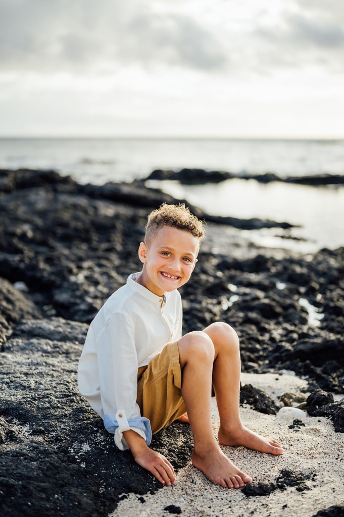boy sitting on the lava rocks at Big Island beach