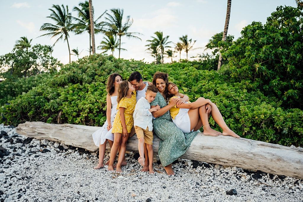 family sitting on a big tree trunk at the beach