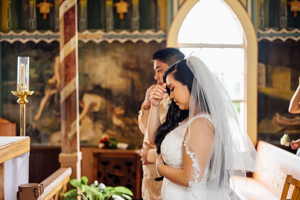 bride and groom doing the sign of the cross 