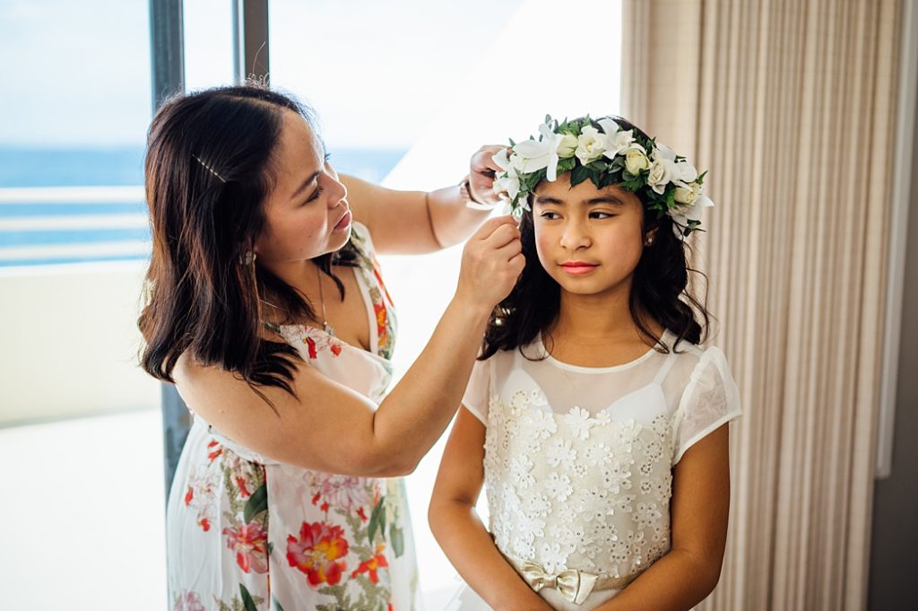 bridesmaid putting on the floral crown to the flower girl