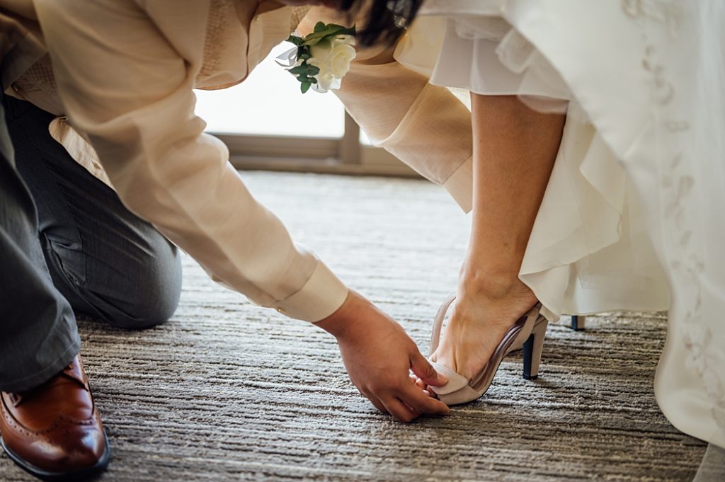 brother's bride helping her wear her wedding shoes