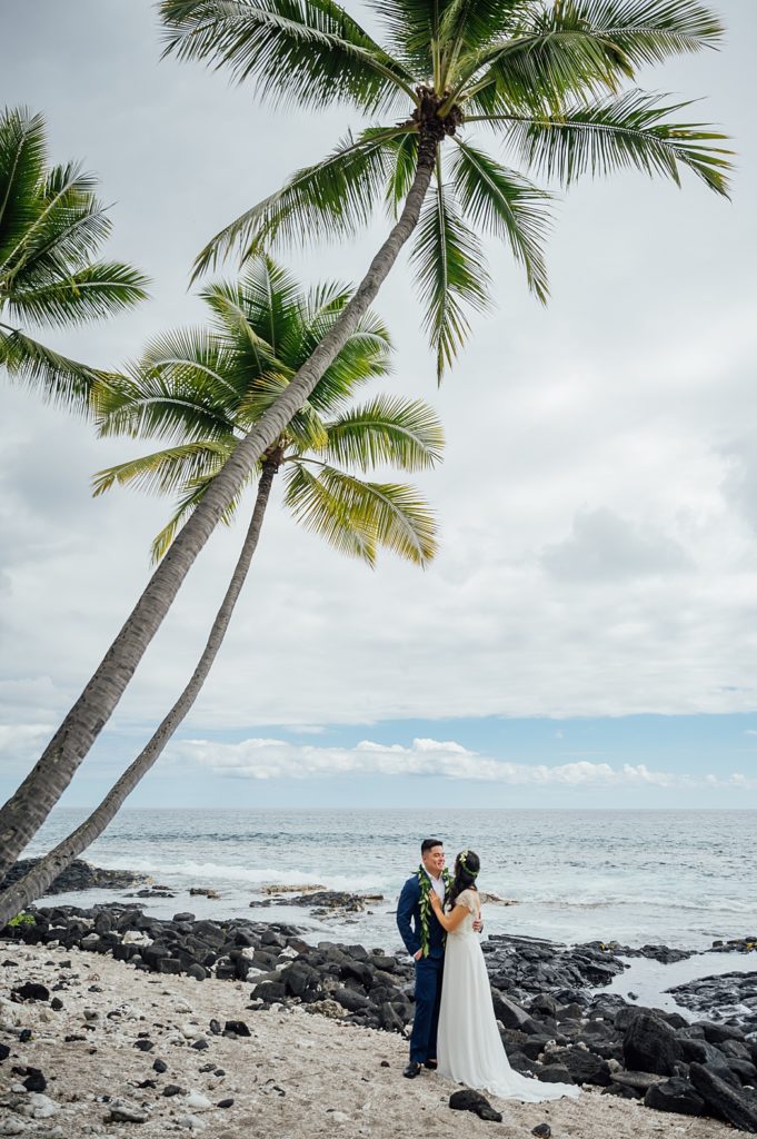 bride and groom under the coconut trees at the beach