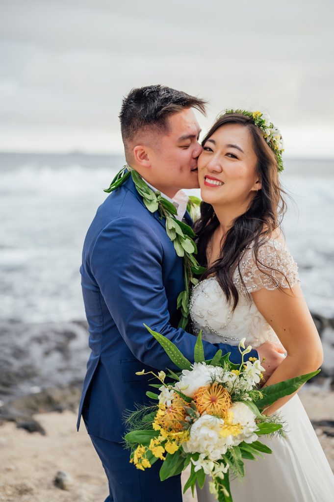 groom kissing bride's cheeks at Hawaii beach