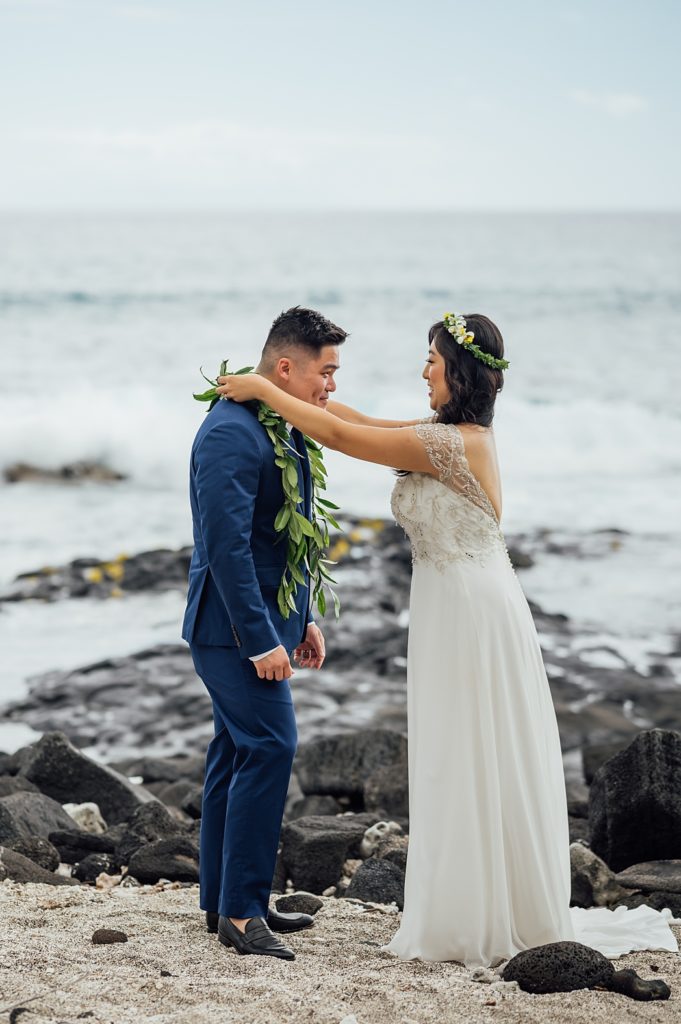 bride putting on the lei to the groom at Hawaii beach