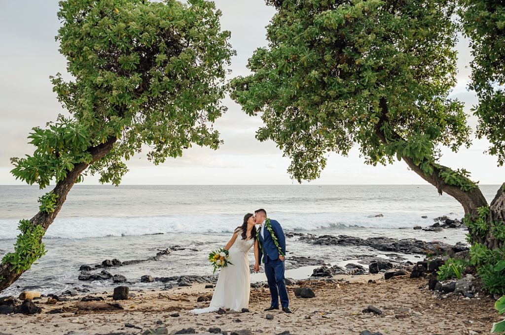 bride and groom kissing under the trees in Hawaii