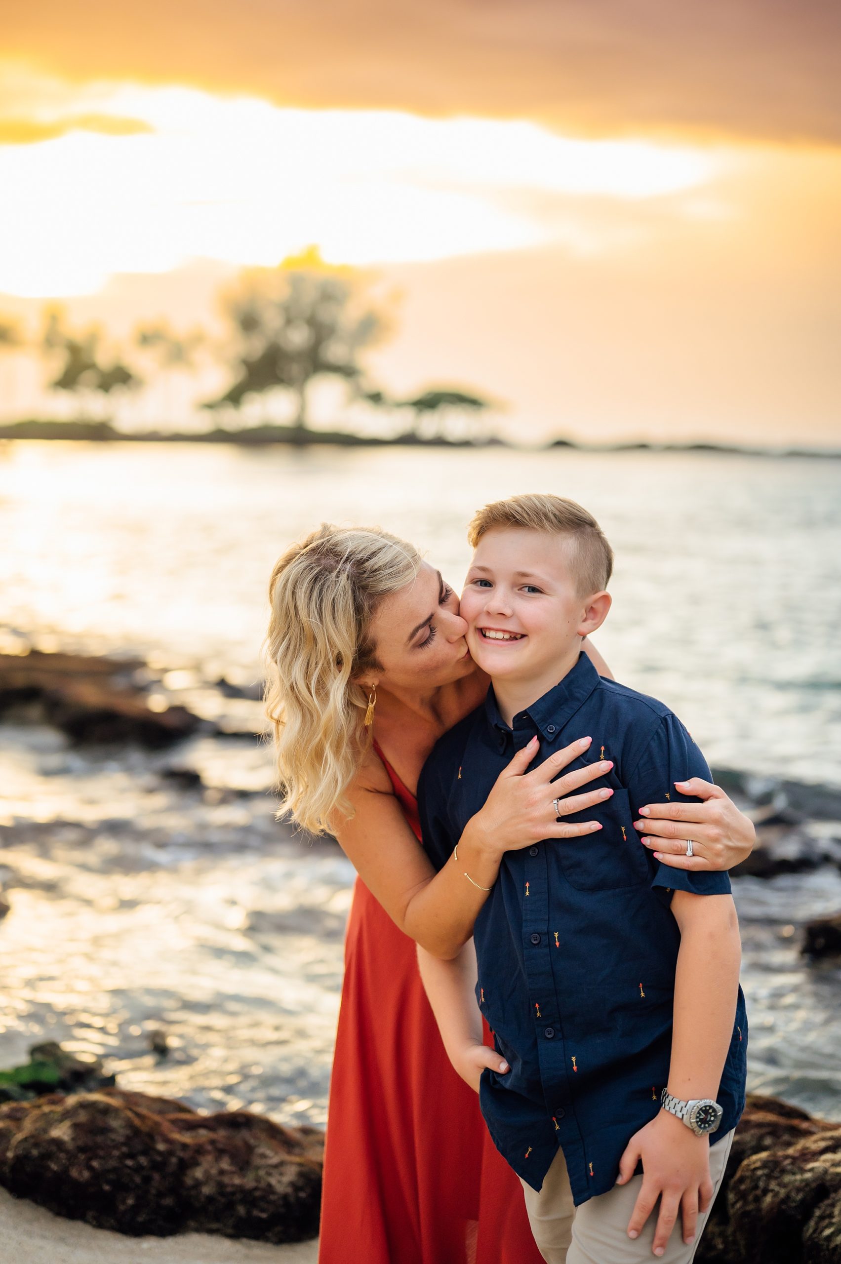 mom kissing son's cheeks during sunset