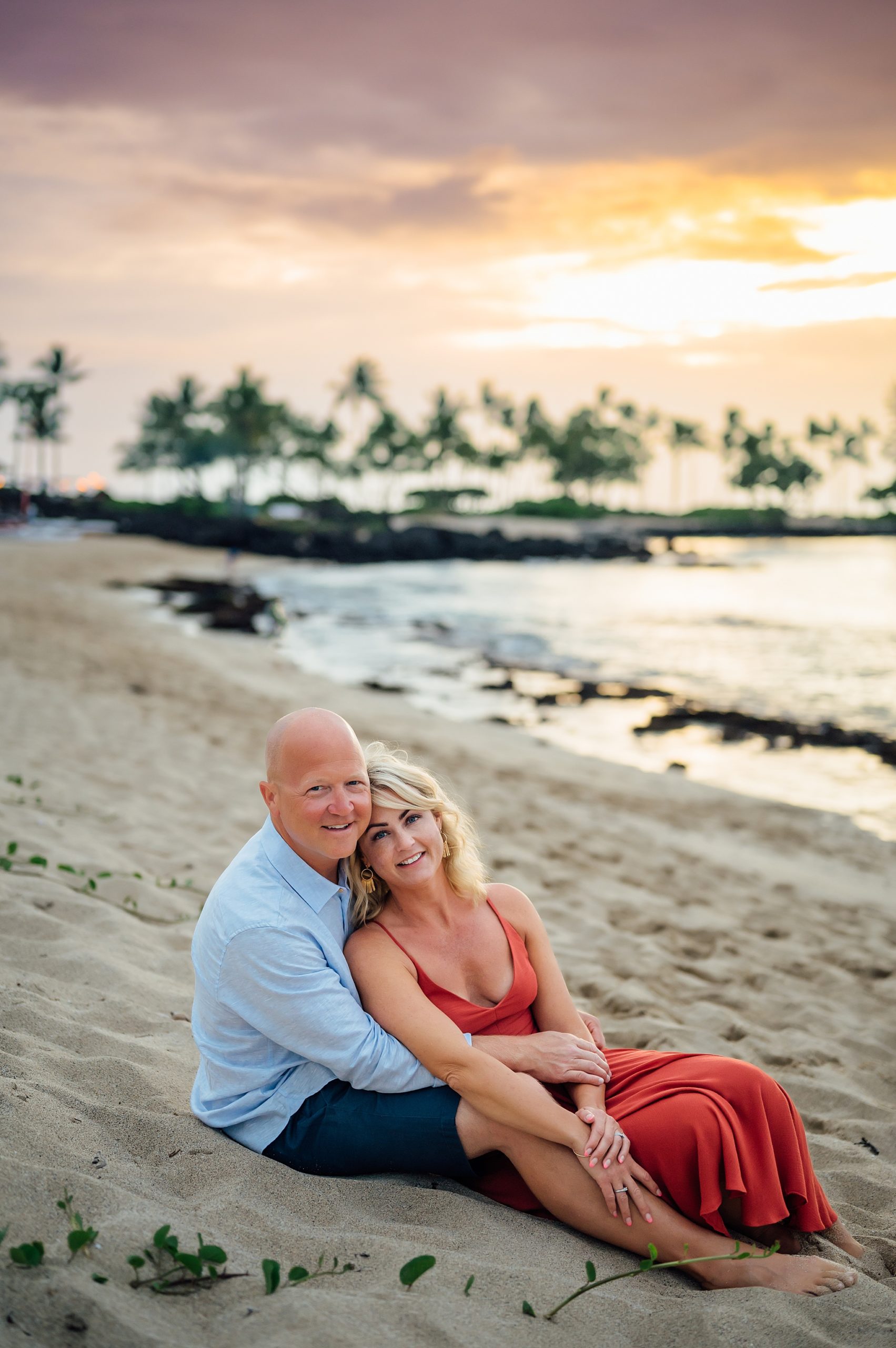 mom and dad sitting on the sand at Hawaii beach