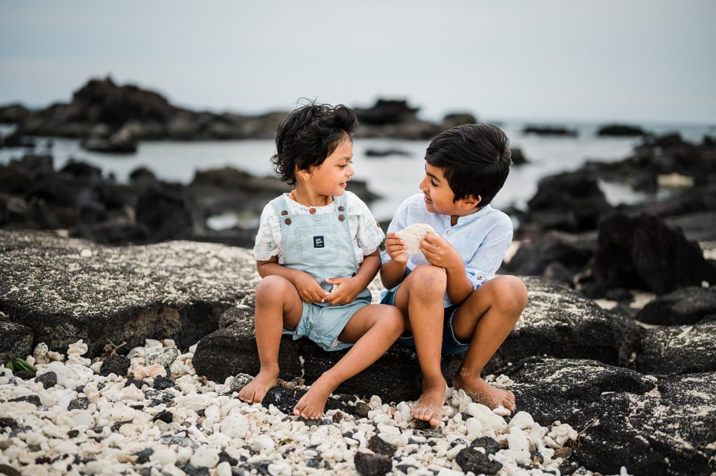 siblings playing on the lava rocks at Hawaii beach 