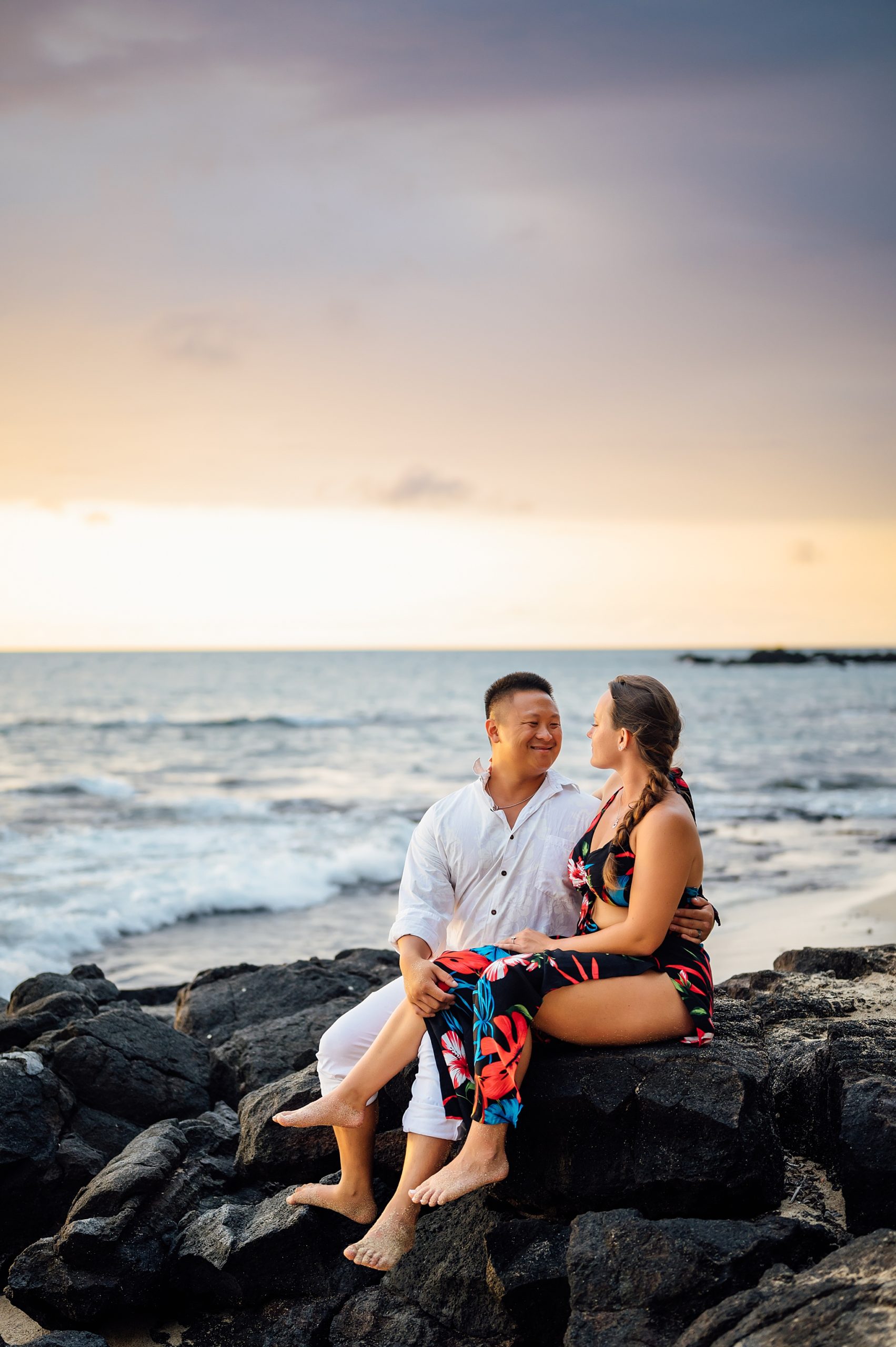 couple sitting on the lava rocks during during sunset