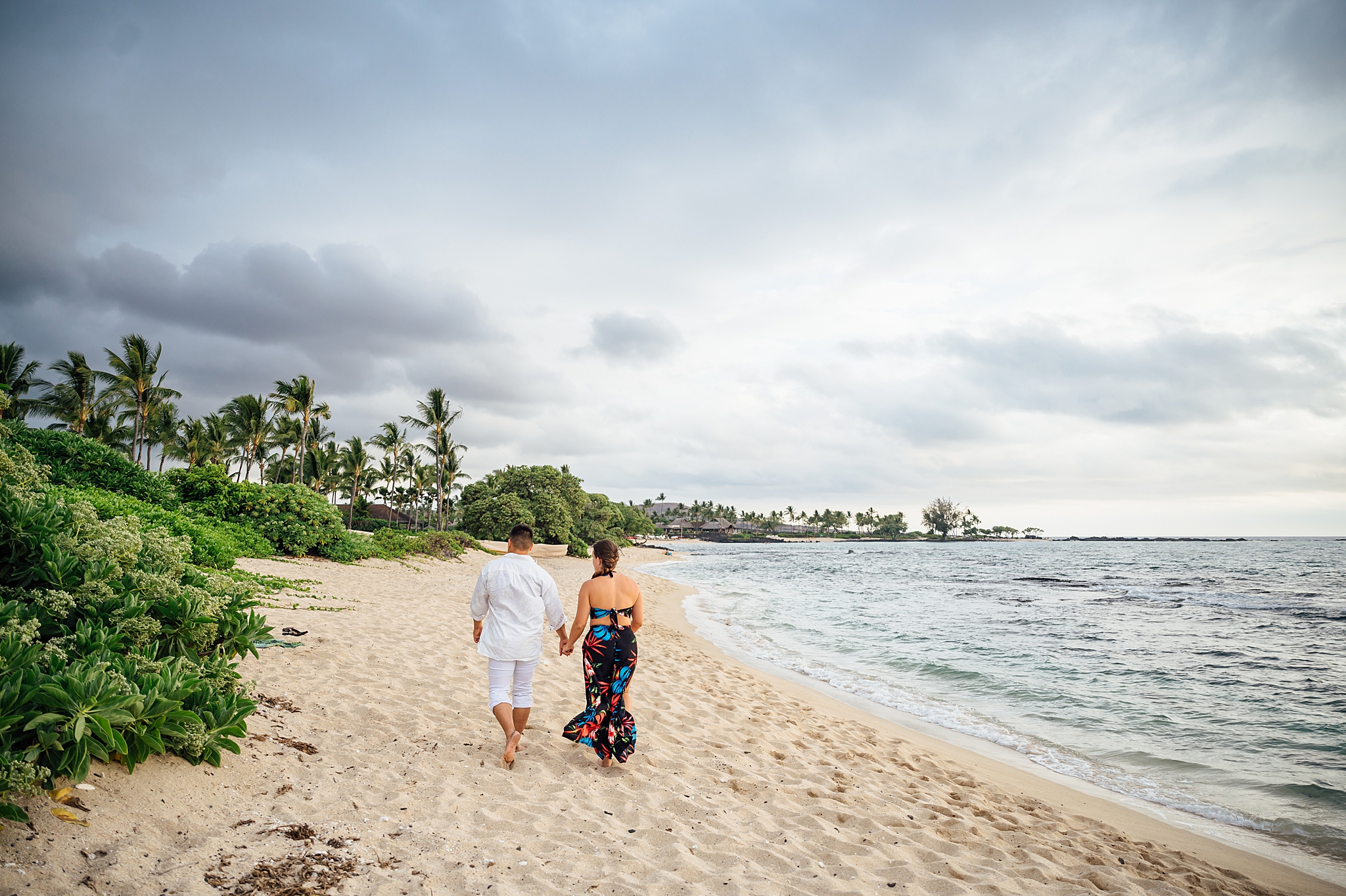 couple walking on the white sand beach
