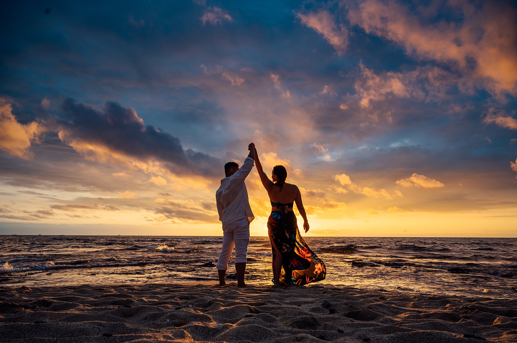 couple raising their hands in front of the breathtaking sunset 